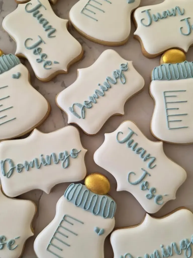 Galletas de nacimiento de mellizos con mamaderas y placas con nombres en celeste