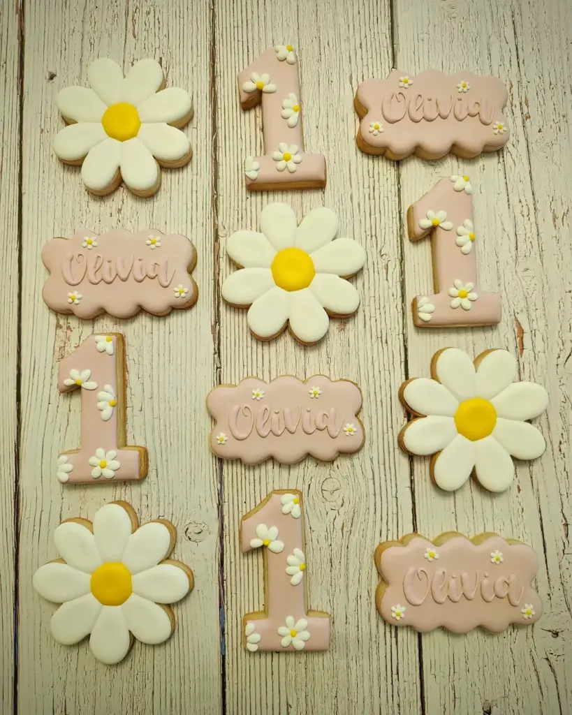 Galletas decoradas para primer cumpleaños con margaritas, número 1 y nombre en rosado
