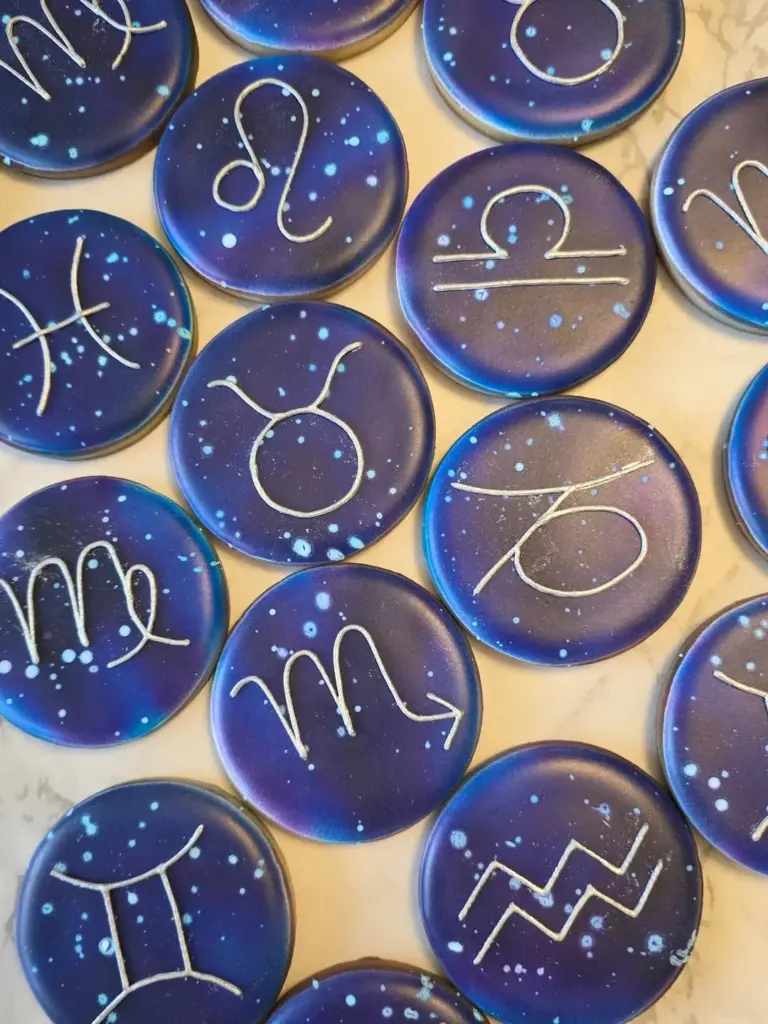 Galletas con signos del zodiaco y constelaciones sobre fondo azul galaxia